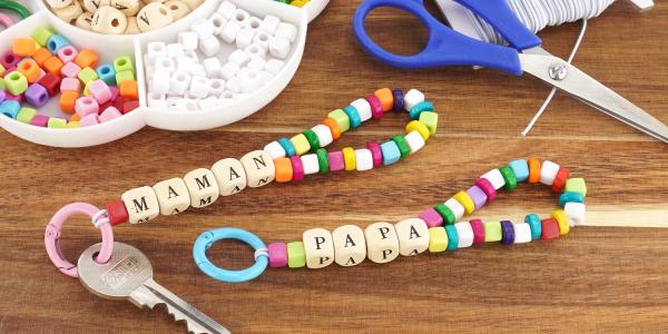 Créez un porte-clés personnalisé avec des perles et les mots PAPA ou MAMAN. Un bricolage affectueux dès 3 ans, à découvrir sur le site.