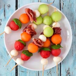 Brochettes d'été avec du melon pastèque concombre et fromage mozzarella ou feta. Une recette simple et délicieuse parfaite pour l'été.