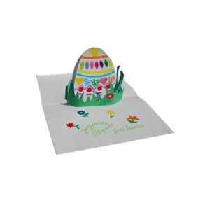 Préparation d'une jolie carte pop-up d'un ?uf de Pâque décoré de gommettes  placé dans l'herbe du jardin . Un bricolage papier en 3D pour la décoration de la maison.