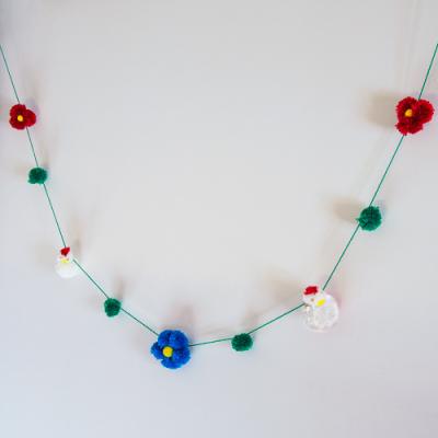 Une guirlande de laine avec des poules et des fleurs en pompons